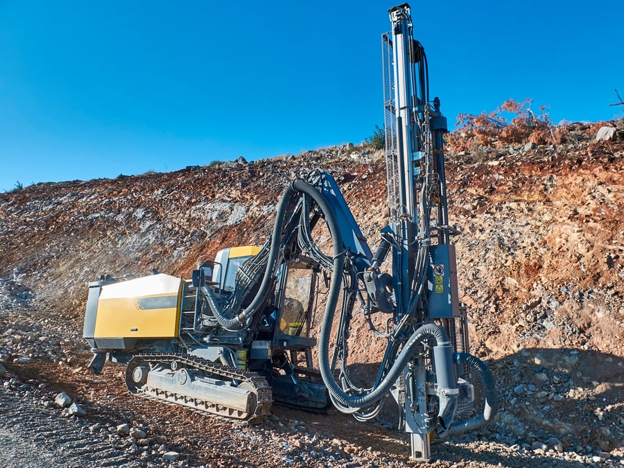 Yellow drilling rig is drilling holes during blasthole drilling operations